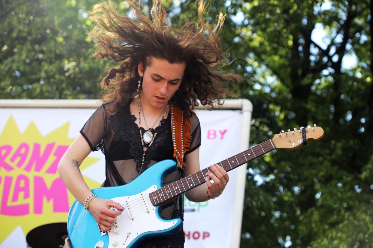Jack Riley, guitarist of My Sister the Heron, plays a tune as their hair blows in the wind in Jonquil Park on Saturday, May 18, 2024. They said they felt awesome while playing
