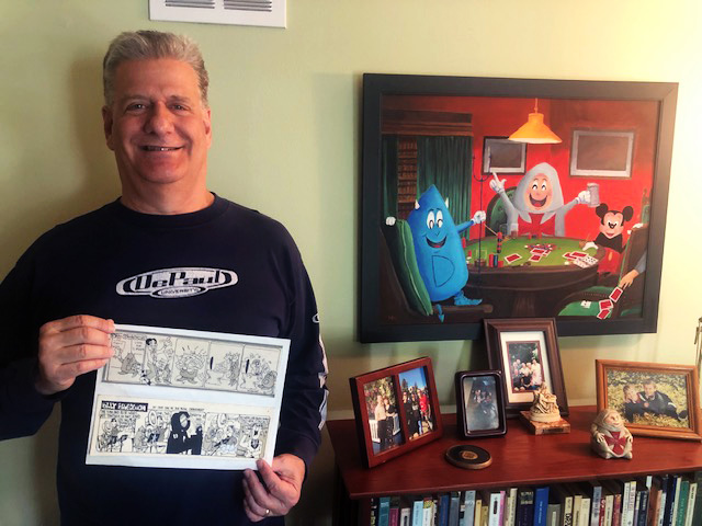 DePaul alum and creator of the Billy Blue Demon character Joe Wozniak poses with one of his strips and his largest oil painting, featuring his original characters Billy and Chris Crusader, as well as Mickey Mouse.