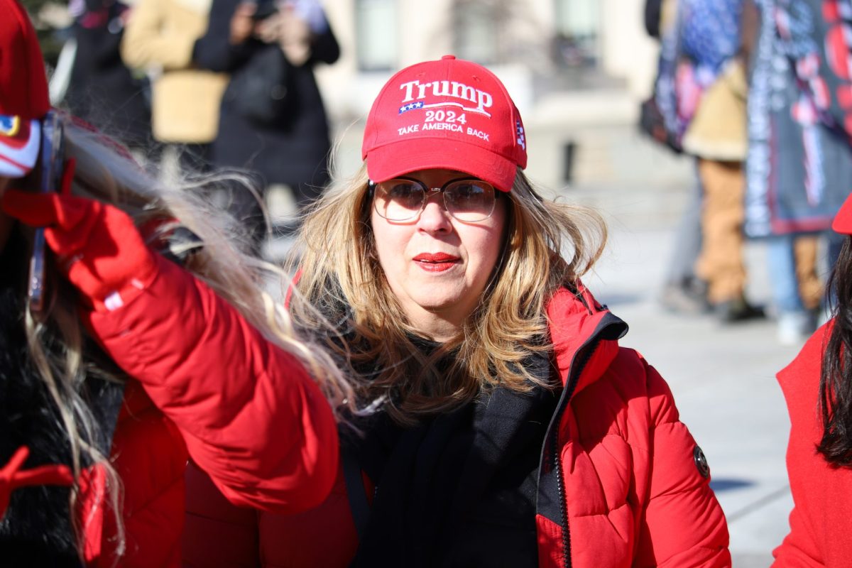 Chabela Rodríguez se sienta en un banco mirando la ruta del desfile de vehículos en la Avenida Pensilvania el 20 de enero de 2025. Votó por el presidente Trump debido a sus políticas sobre inmigración, seguridad fronteriza y economía.