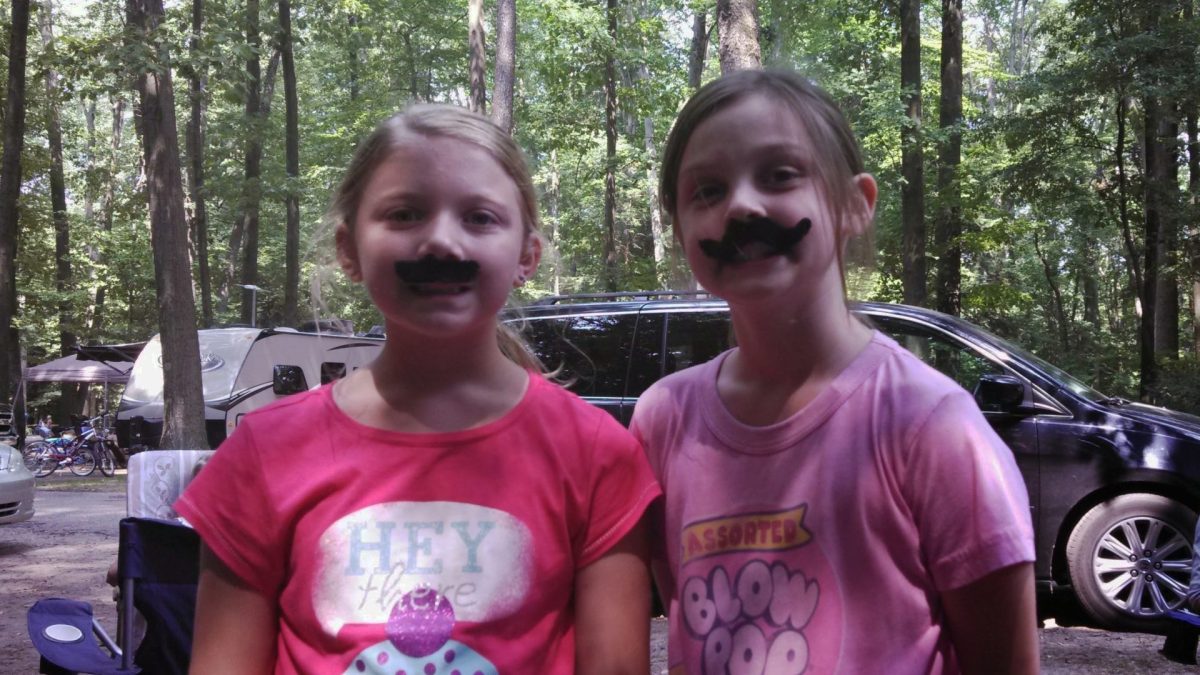 8-year-old Brielle Kohlbeck and Olivia Ward pose with fake mustaches in a campground. Kohlbeck brought Ward camping with her family every summer when they were kids. (photo provided by Brielle Kohlbeck)