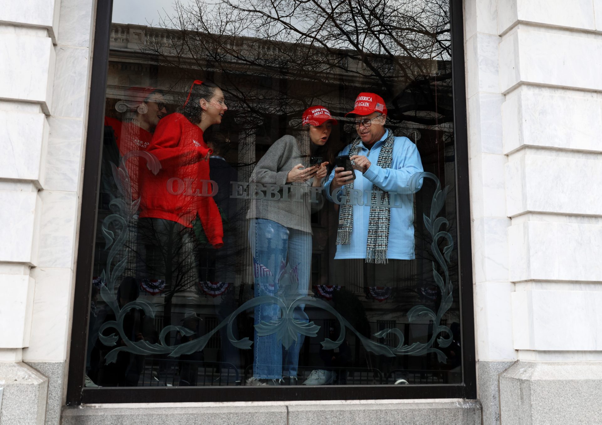 Trump supporters stand in the window of a restaurant near the White House to watch the inauguration parade on Monday, Jan. 20, 2025, in Washington, D.C. Due to cold weather, most inaugural events were moved to indoor venues.