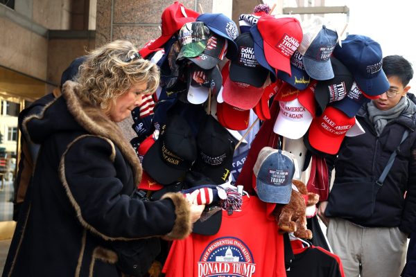 A Trump supporter browses merchandise at a street vendor during his Inauguration on Monday, Jan. 20, 2025, in Washington, D.C.. The streets were filled with all sorts of outfits, ranging from furs to face paints.

