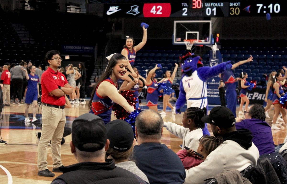 A DePaul cheerleader hands a t-shirt to a young fan in the stands on Sunday, Jan. 12, 2025, at Wintrust Arena. “A true fan always supports their team,” Jill Pizzotti, interim head coach, said.