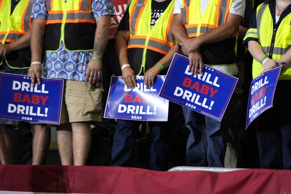 Attendees holding signs listen as Republican presidential nominee former President Donald Trump speaks during a campaign event, Aug. 29, 2024, in Potterville, Mich.