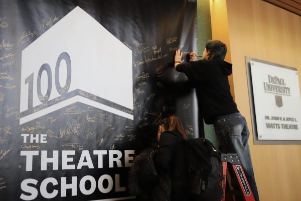 A theatre school student signs a banner hung in the lobby of the school commemorating the 100th anniversary of the Goodman School of Drama on Wednesday, Jan. 29, 2025. Notable alumni and supporters also signed the banner, including former DePaul President Dennis Holtschneider.