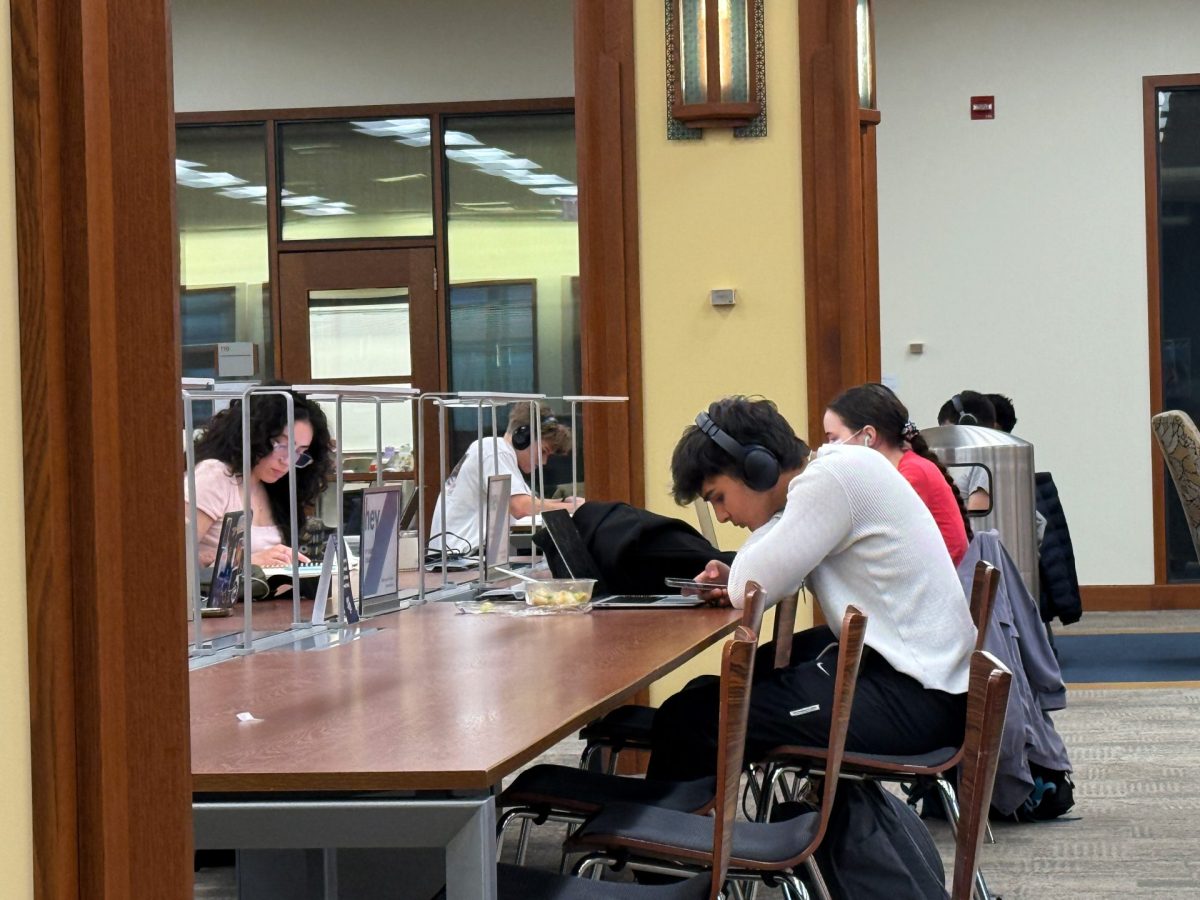 A DePaul student with headphones checks his phone on Thursday, Feb. 27, 2025, at the Richardson Library. Most students in the John T. Richardson library wear headphones.