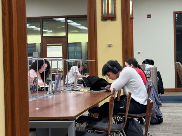 A DePaul student with headphones checks his phone on Thursday, Feb. 27, 2025, at the Richardson Library. Most students in the John T. Richardson library wear headphones.