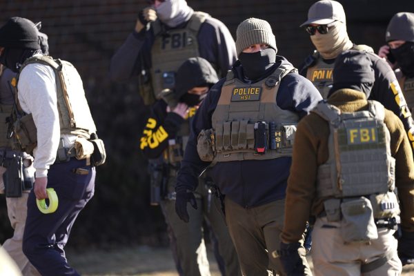 Law officials enter an apartment complex during a raid Wednesday, Feb. 5, 2025, in east Denver. (David Zalubowski / Associated Press)