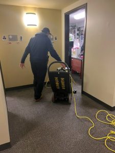 A maintenance man in Ozanam Hall uses a squeegee vacuum in Carissa Janey's dorm to clean the flooded carpets on Tuesday, Feb. 4, 2025. Students living in the affected dorm rooms have been temporarily rehoused. 