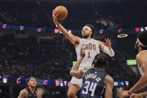 Cleveland Cavaliers guard Max Strus (1) goes up for a shot between Orlando Magic forward Paolo Banchero, left, and center Wendell Carter Jr. (34) in the first half of an NBA basketball game Sunday, March 16, 2025, in Cleveland. (AP Photo/Sue Ogrocki)