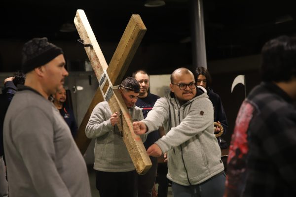 Miembros de la comunidad que practican la procesión siguen a Eduardo "Eddie" Bahena mientras carga la gran cruz dentro del sótano de la Iglesia de San Pío el 11 de abril de 2025. El día del Vía Crucis, la procesión recorrerá la calle 18 hasta llegar al Parque Harrison. Este será el 48.º año del Vía Crucis de Pilsen, que comenzó en 1977.