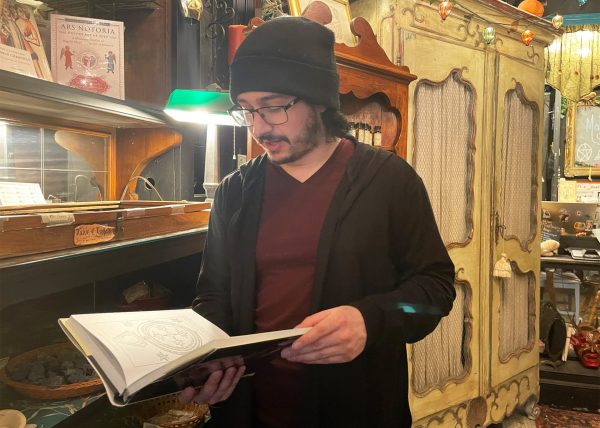 Lucas Lona holds “Techniques of Solomonic Magic” at the Malliway Bros. Shop in Rodgers Park on March 7, 2025. Lona says this is one of his favorite items in the store. 