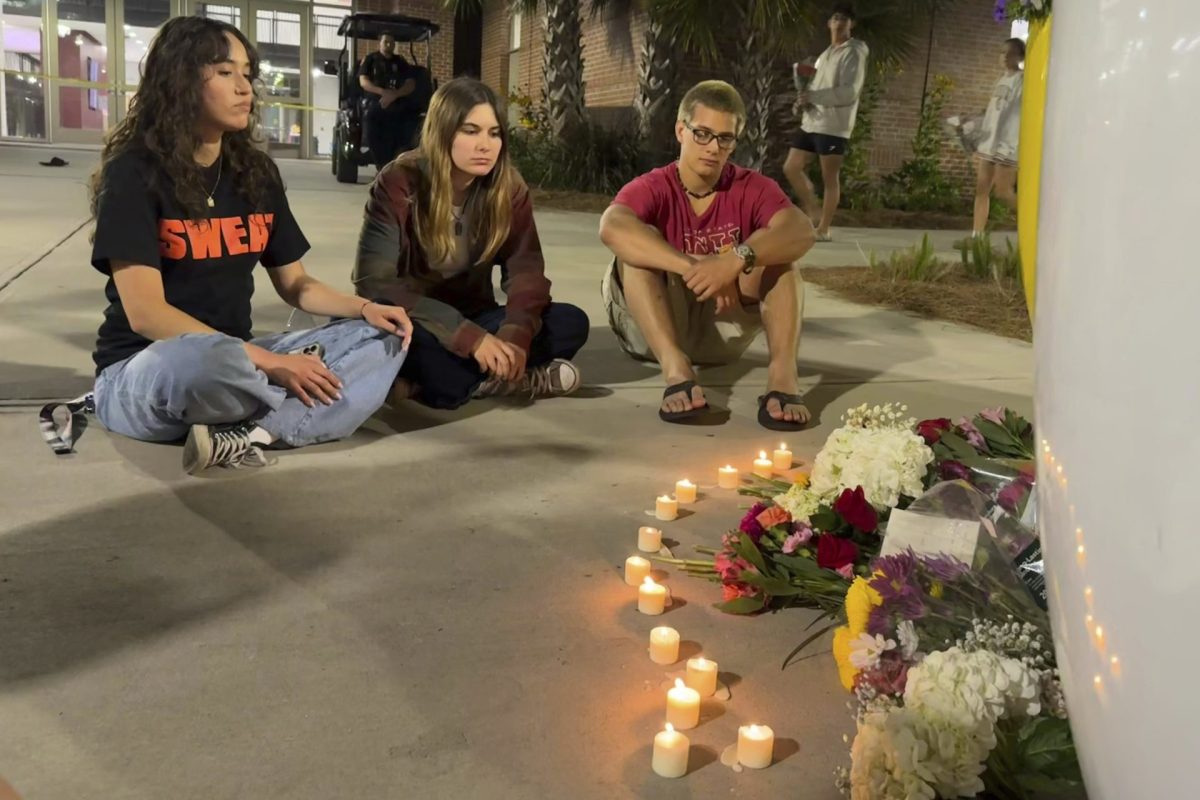 People sit in front of a makeshift memorial outside the student union at Florida State University, Thursday, April 17, 2025, in Tallahassee, Fla., following a campus shooting. 