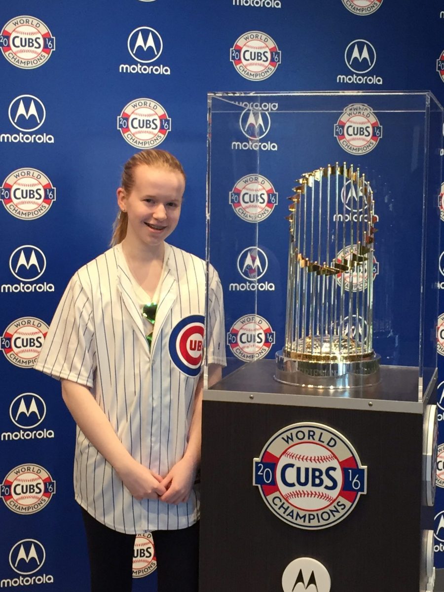 Peyton Hopp poses next to the Chicago Cubs 2016 World Series trophy on Sunday, April 29, 2018 at Wrigley Field. Hopp is a Chicago Cubs fan.